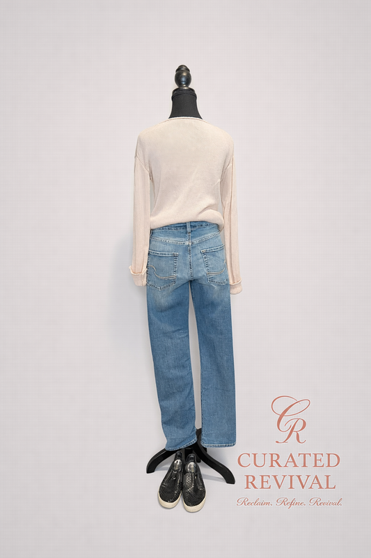 Mannequin wearing a cream sweater and blue jeans with 'Curated Revival' branding on a light gray background.