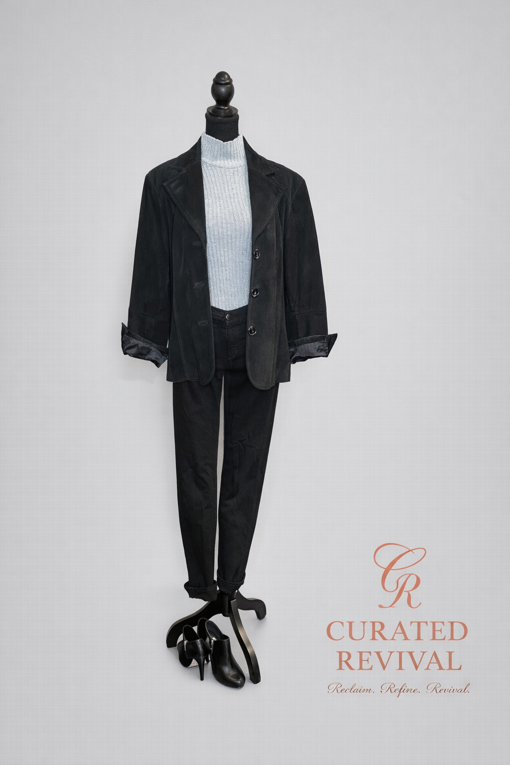 Mannequin wearing a black suit with a white shirt on a gray background, branded 'Curated Revival'.