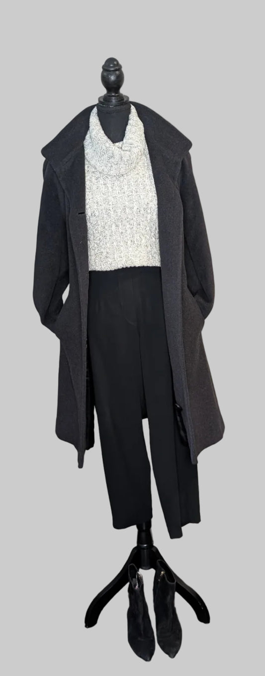Mannequin wearing a black coat over a white top on a gray background
