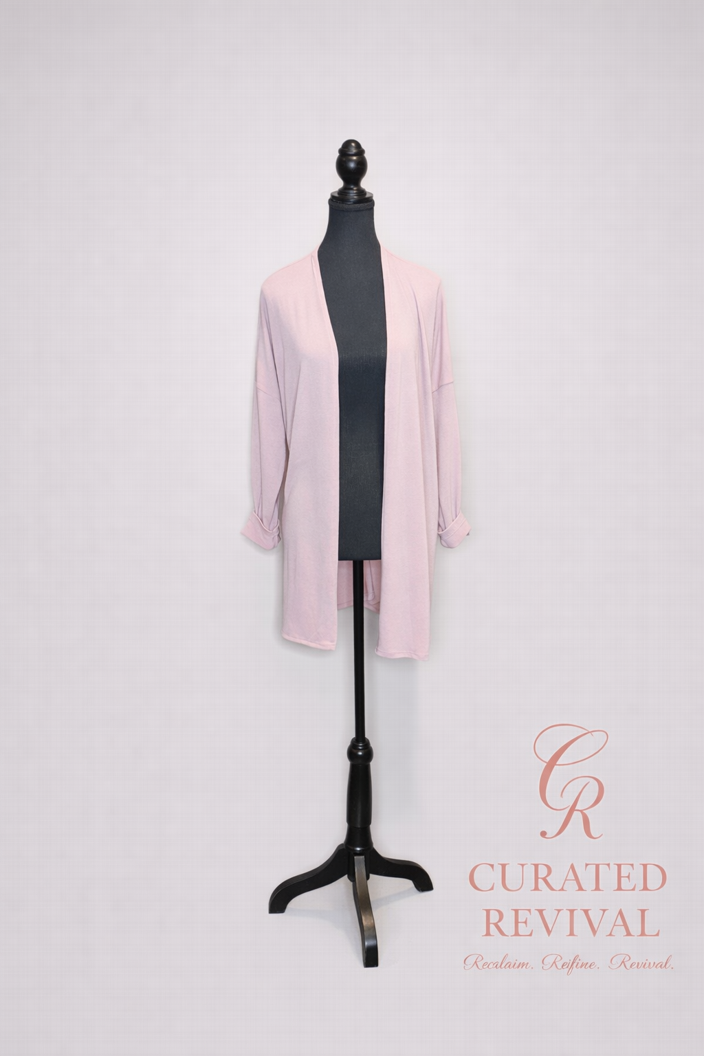 Mannequin wearing a light pink cardigan with 'Curated Revival' branding on a white background