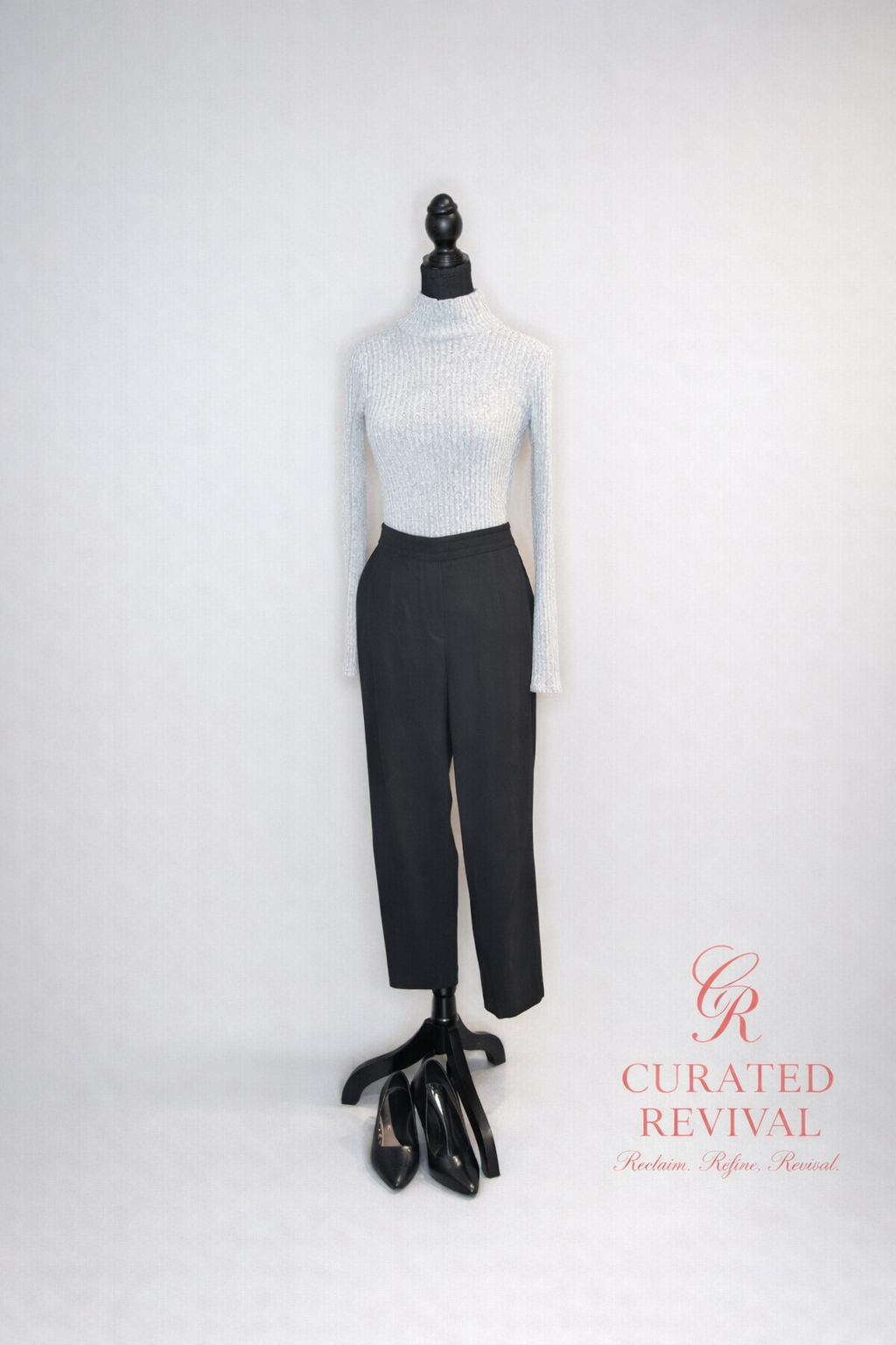 Mannequin wearing a light blue turtleneck and black pants with 'Curated Revival' branding on a white background.