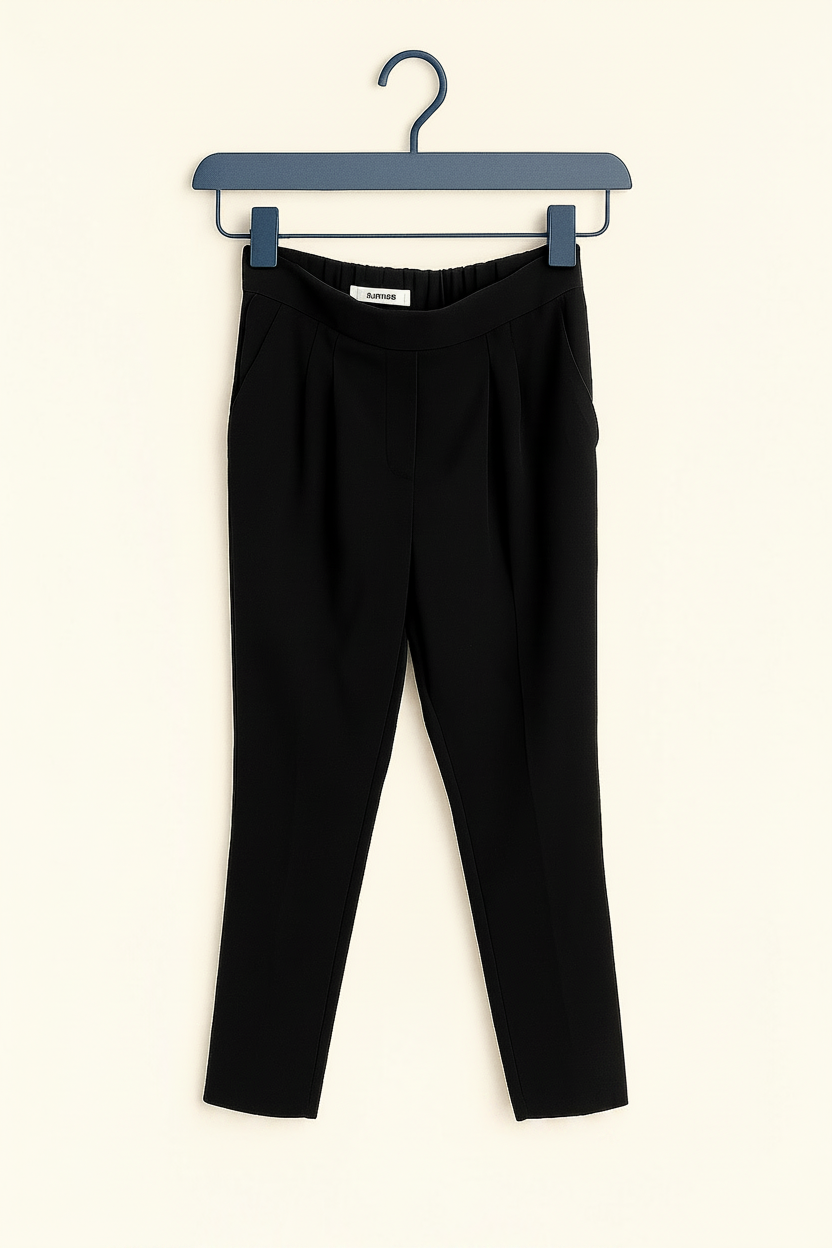 Black pants on a hanger with 'Curated Revival' branding.