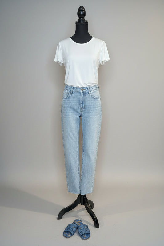 Mannequin wearing a white t-shirt and light blue jeans with shoes on the floor.