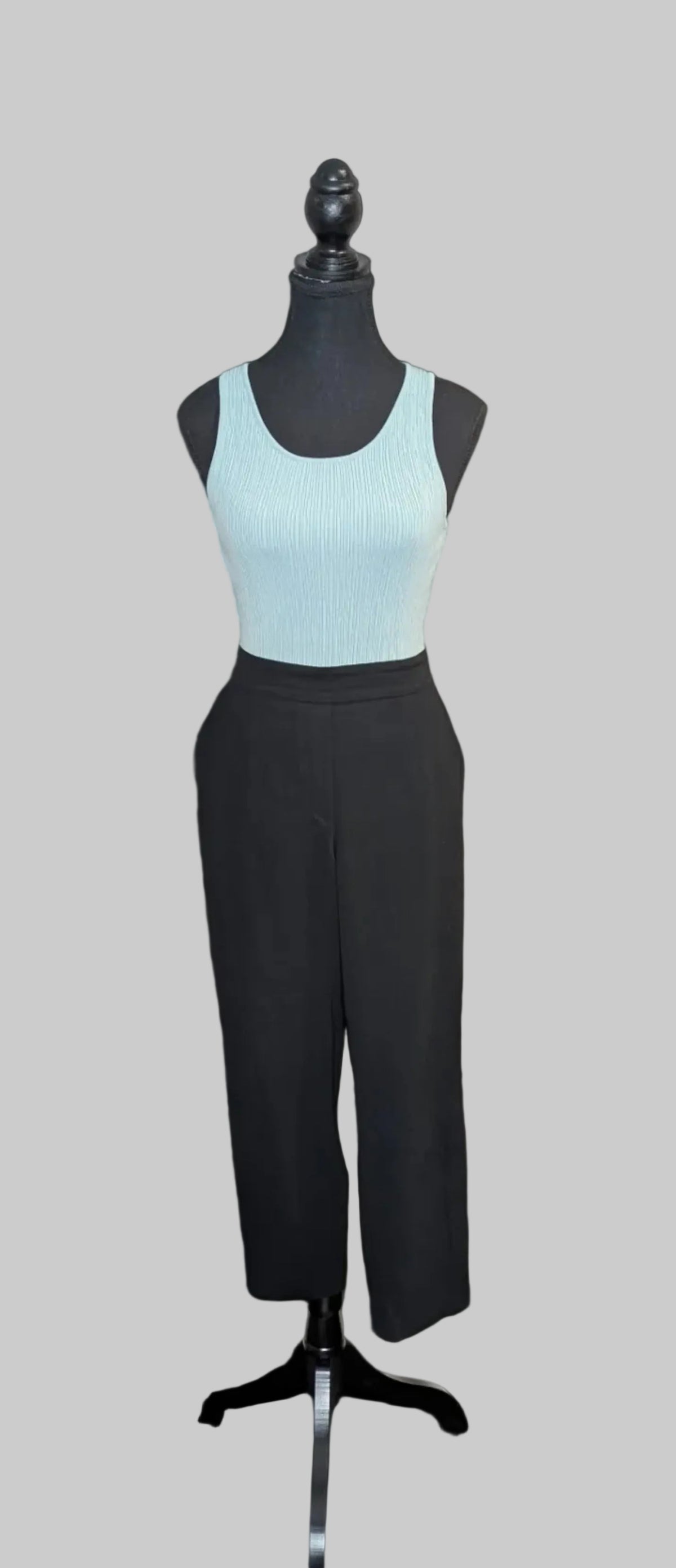 Mannequin wearing a light blue tank top and black pants on a gray background
