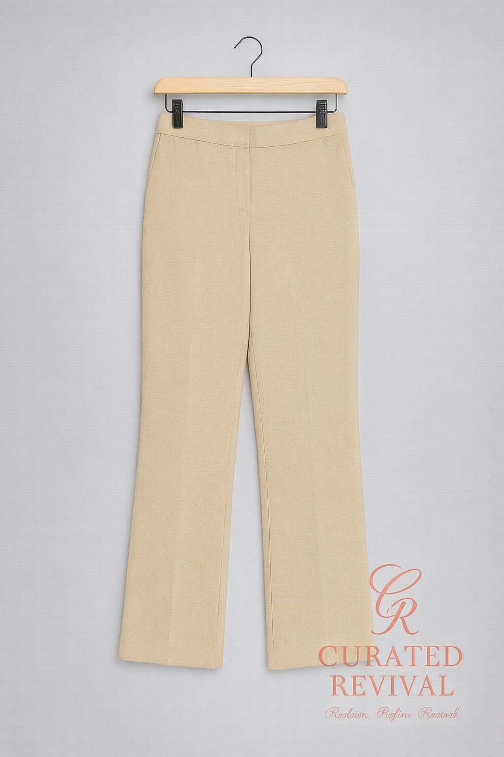 Beige pants on a hanger against a gray background with 'Curated Revival' branding.