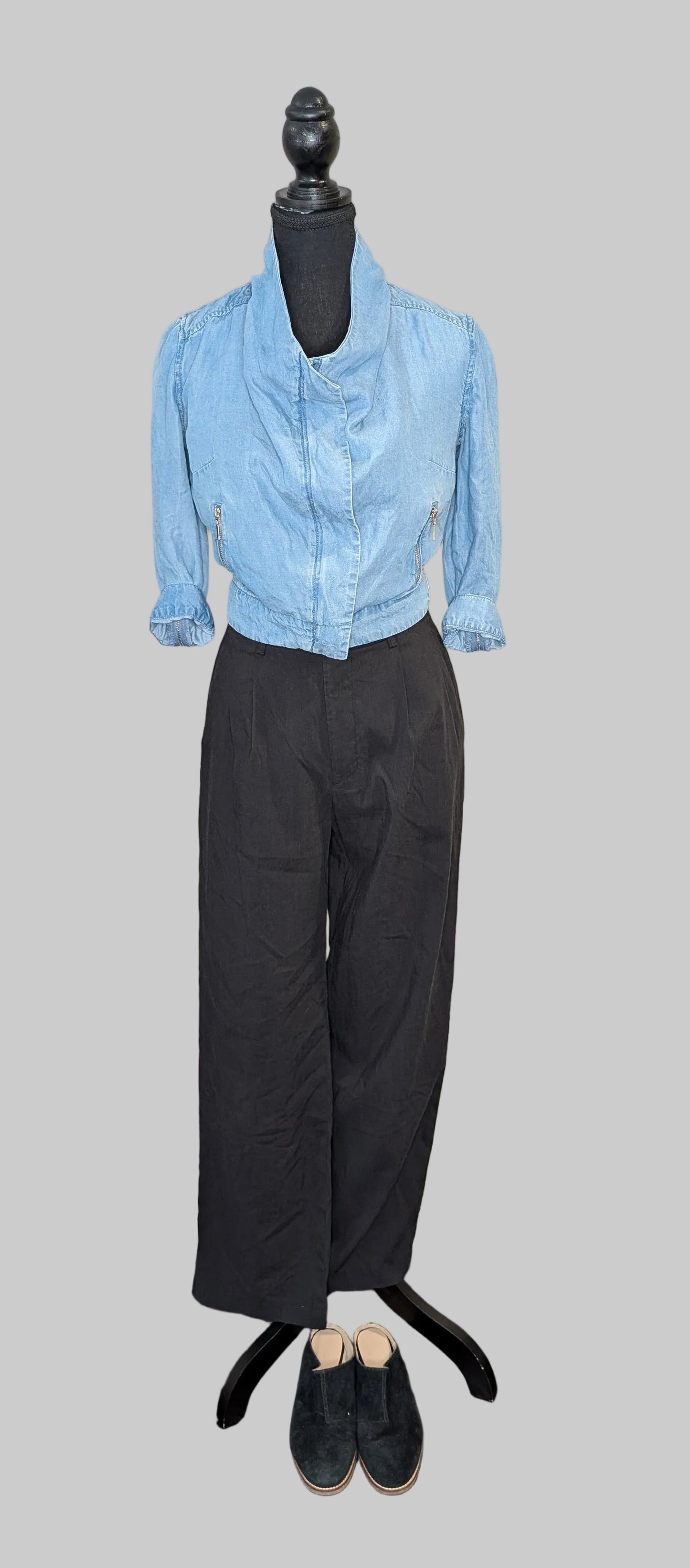 Mannequin wearing a light blue shirt and black pants on a gray background
