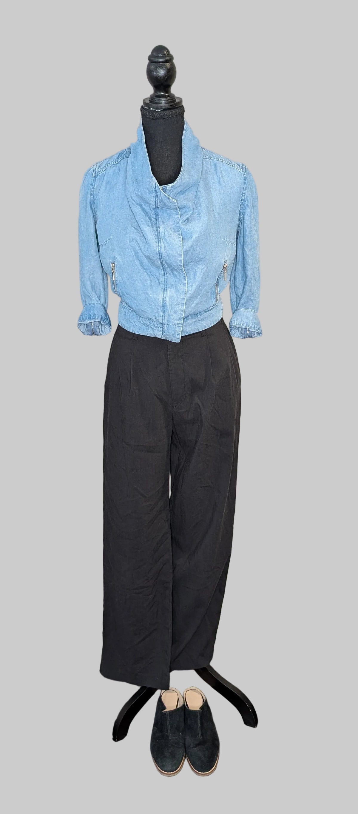 Mannequin wearing a light blue shirt and black pants on a gray background