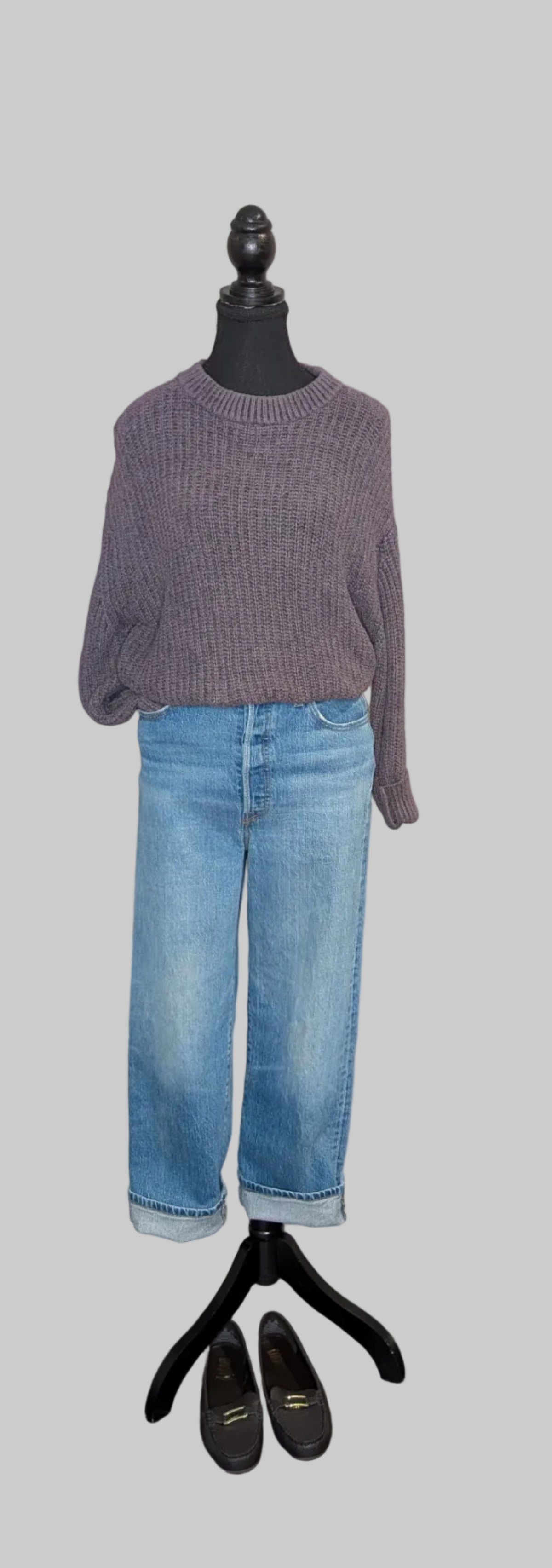 Mannequin wearing a gray sweater and blue jeans with black shoes on a light gray background