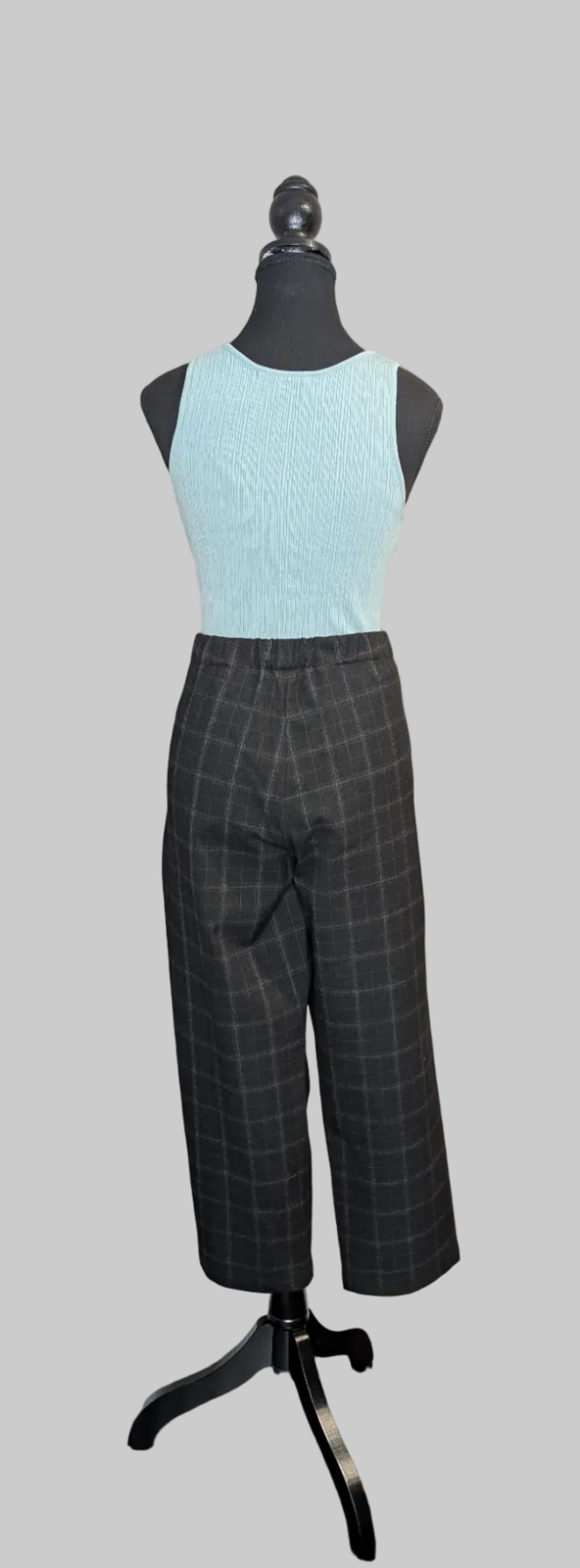 Mannequin wearing a light blue top and dark plaid pants on a gray background