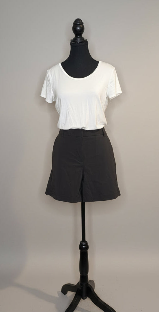 Mannequin wearing a white t-shirt and black shorts against a plain wall.