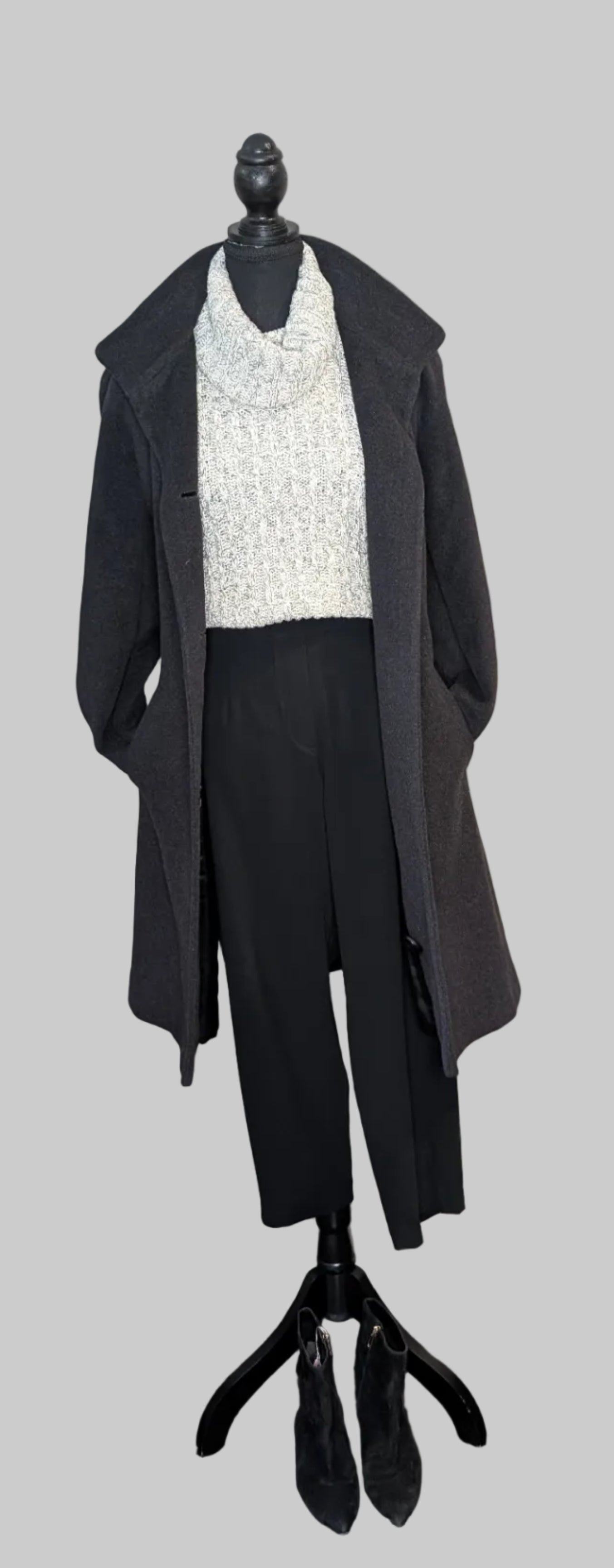 Mannequin wearing a black coat over a white top on a gray background