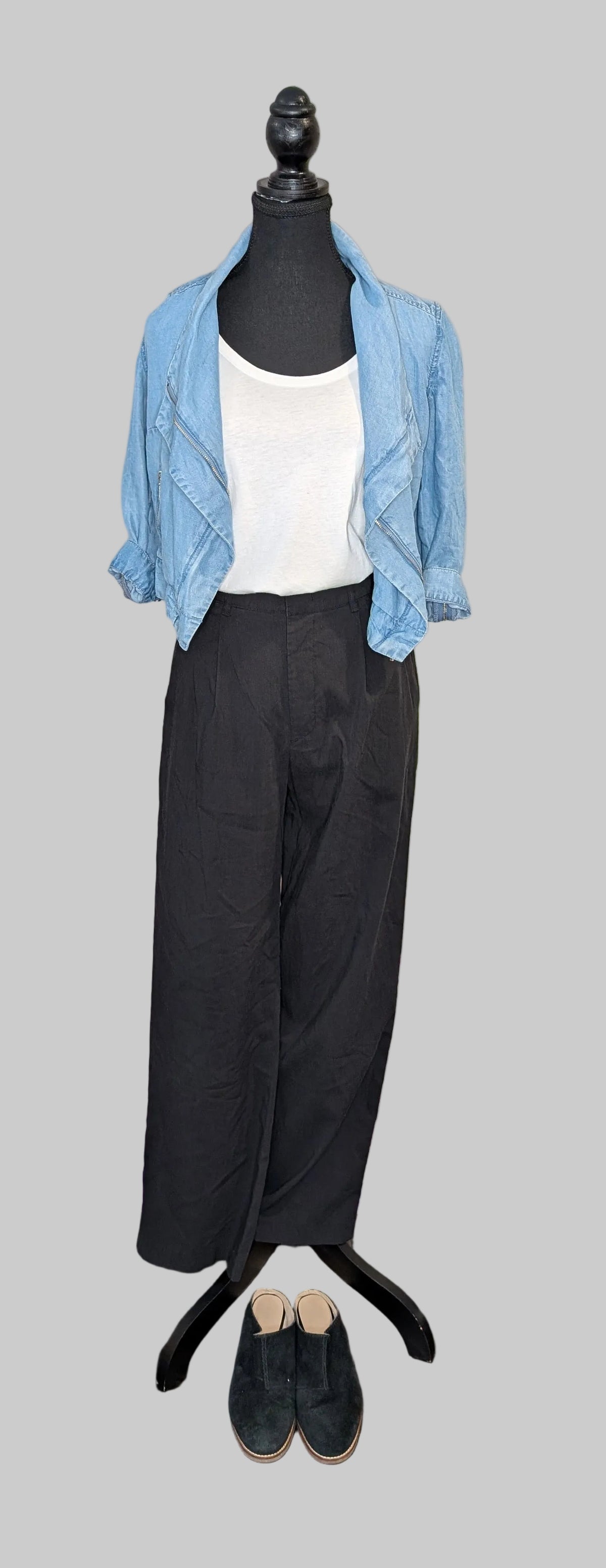 Mannequin wearing a light blue cardigan, white shirt, black pants, and black shoes on a gray background