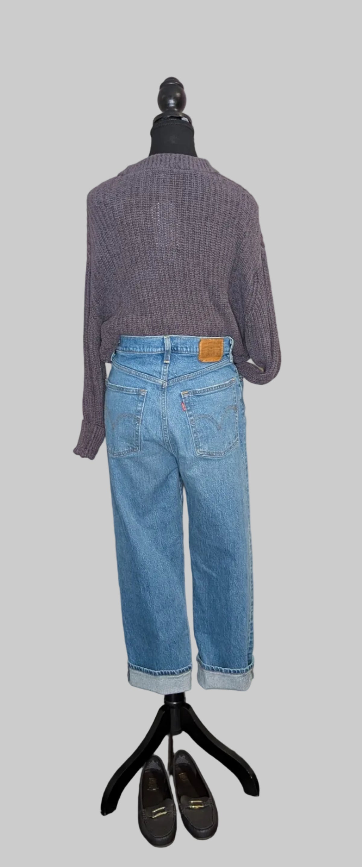 Mannequin wearing a purple sweater and blue jeans on a gray background