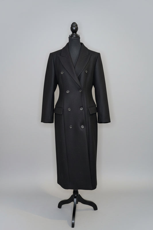 Black double-breasted coat on a mannequin against a plain background