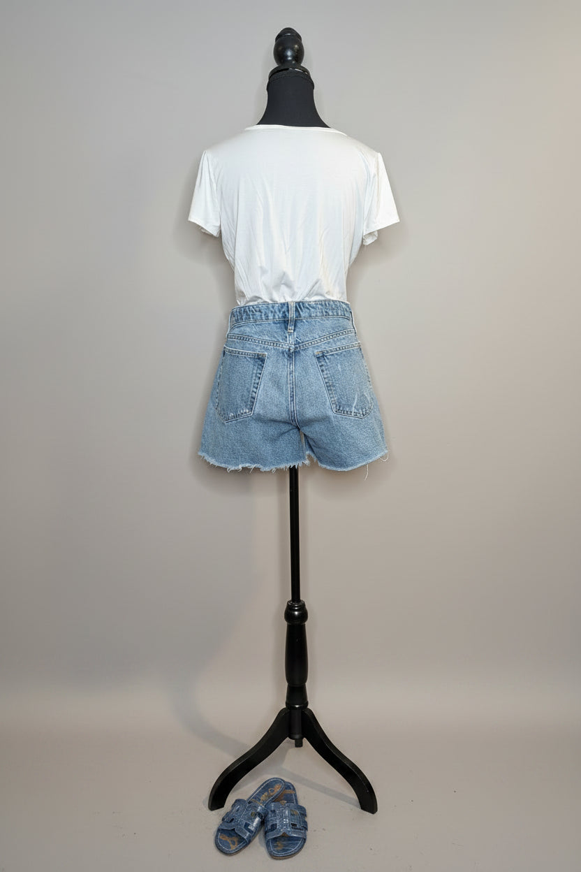Mannequin wearing a white t-shirt and blue shorts with a plain background