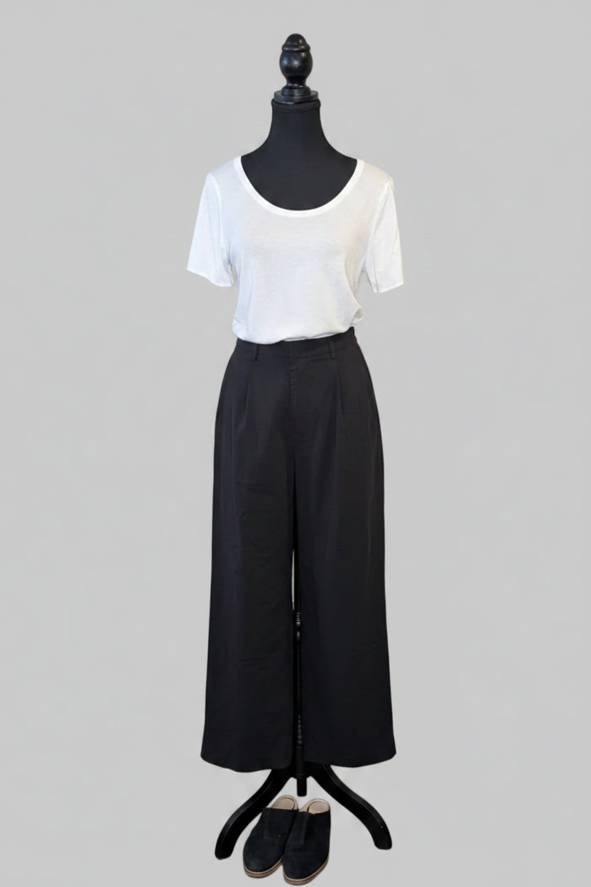 Mannequin wearing a white top and black pants on a gray background
