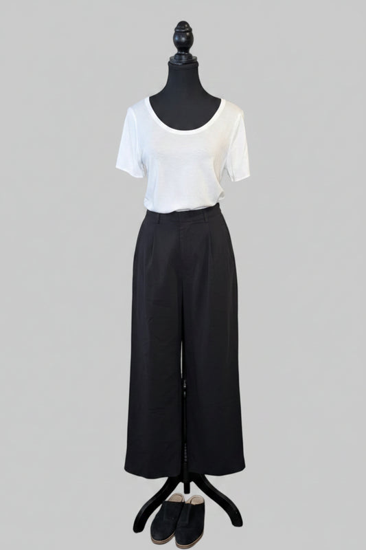 Mannequin wearing a white top and black pants on a gray background