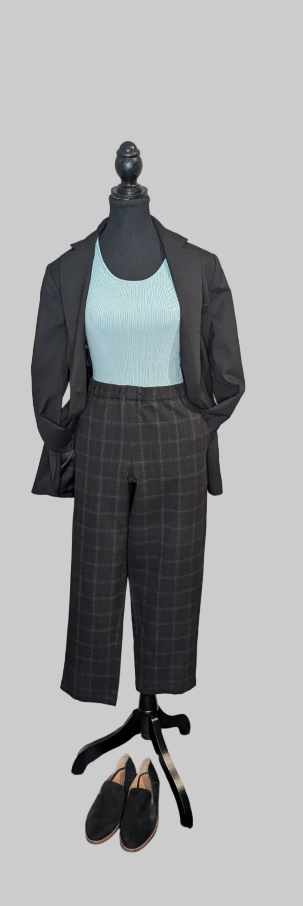 Mannequin wearing a gray suit with a light blue top on a gray background