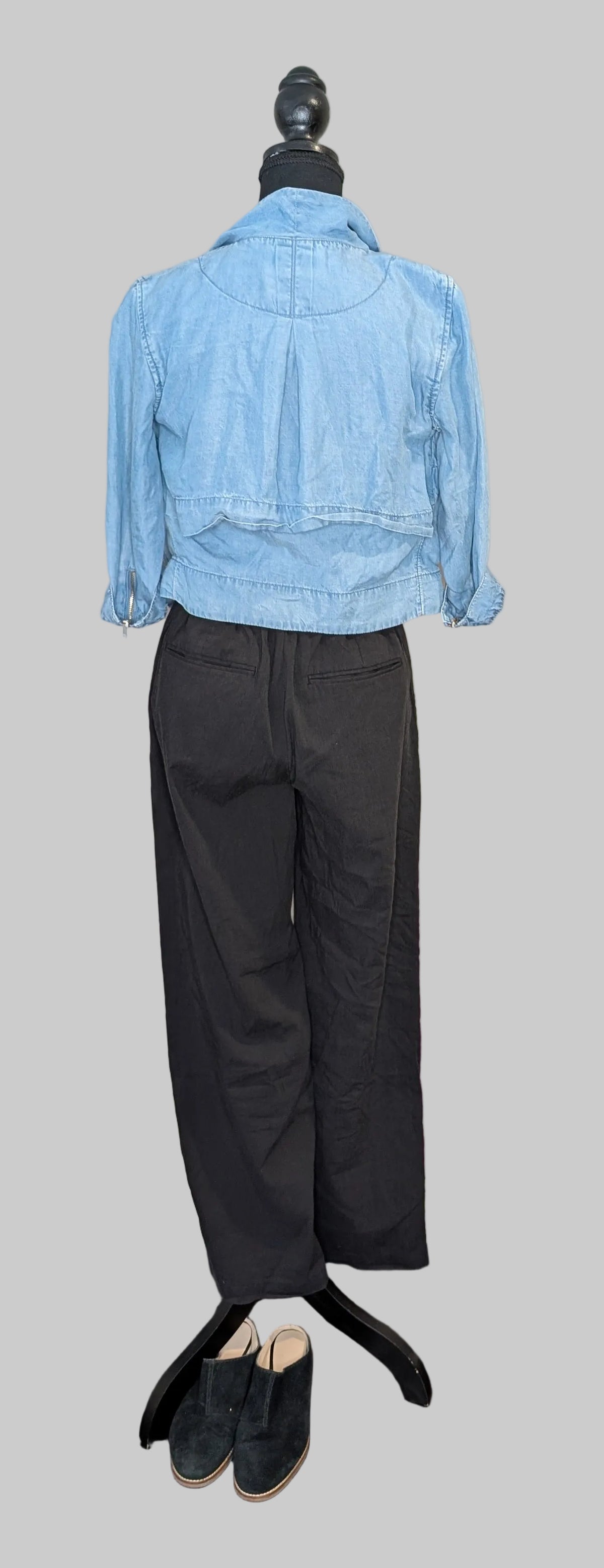 Mannequin wearing a light blue denim jacket and black pants on a gray background
